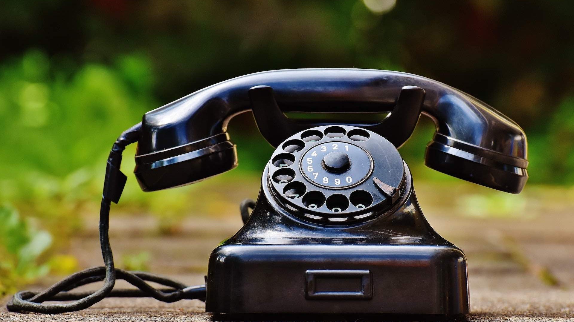 Vintage Black phone handset sitting on the ground outside