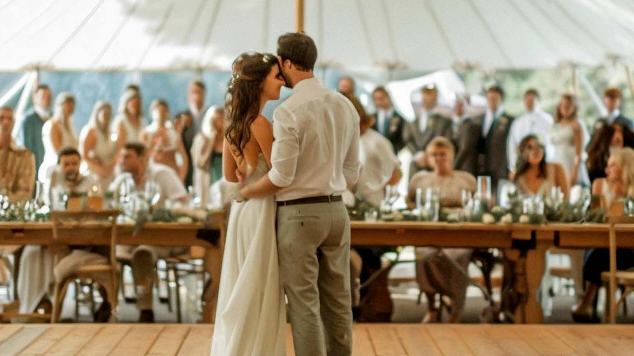 Outdoor wedding tent with couple on dance floor.