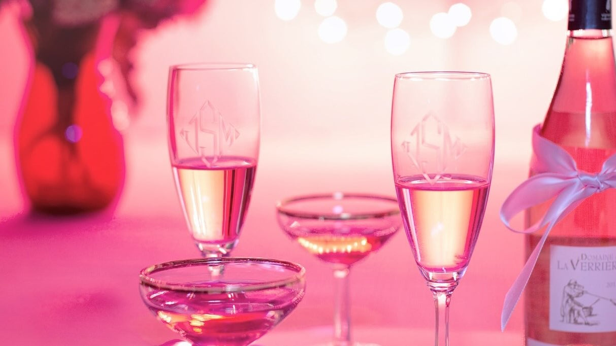 Wine and champaign flutes in a fun pink lit background.