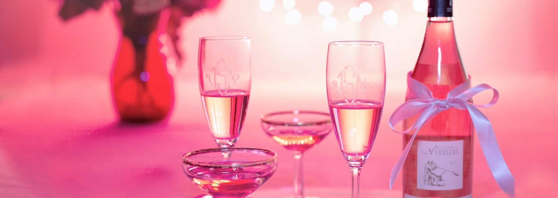 Wine and champaign flutes in a fun pink lit background.