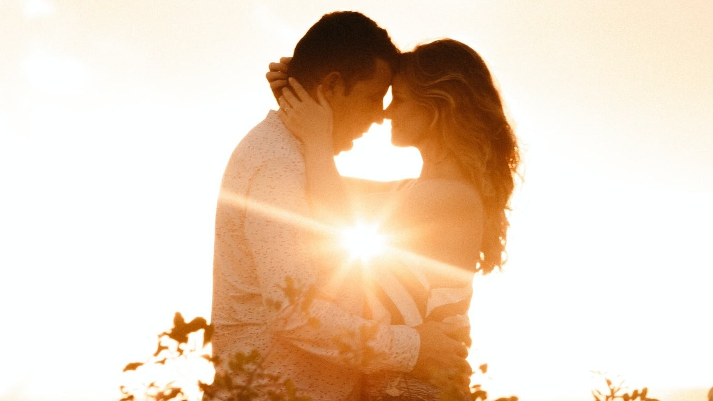 Couple gazing into each others eyes while silhouetted by the sun.