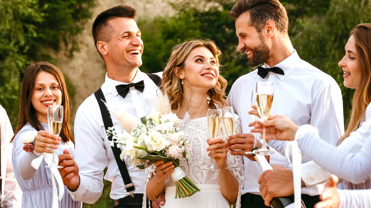 Bride and groom are surrounded by their wedding party making a toast.