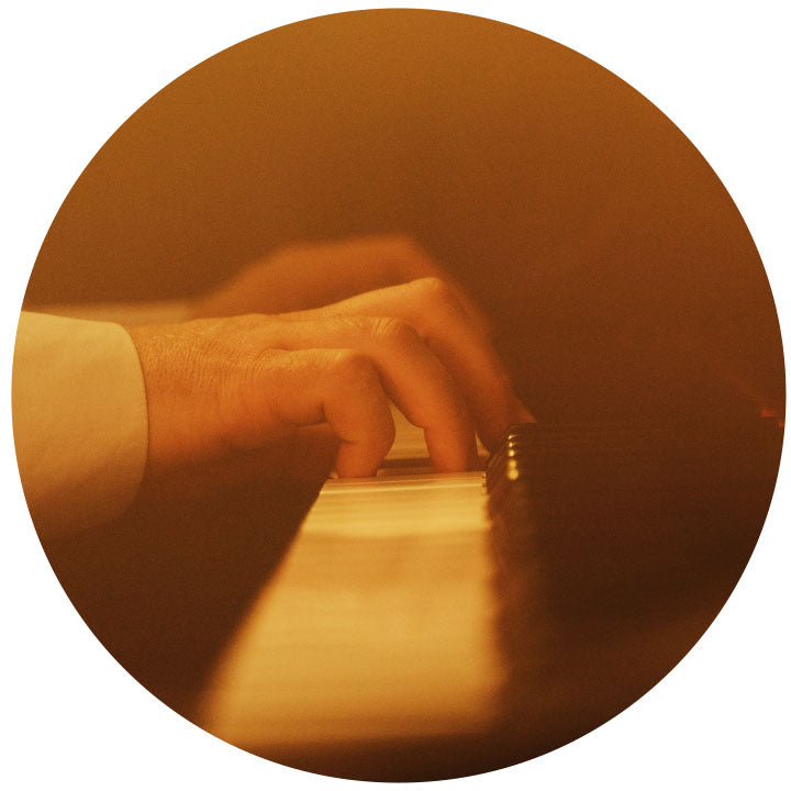 Close up of hands playing a piano. With a yellow light shining over the top