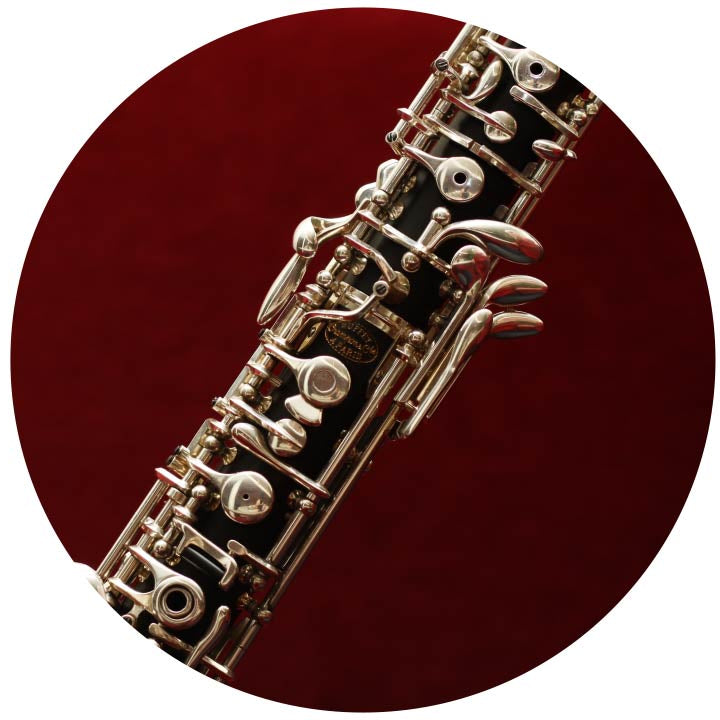 Middle section of oboe with silver plated keys. On a red background