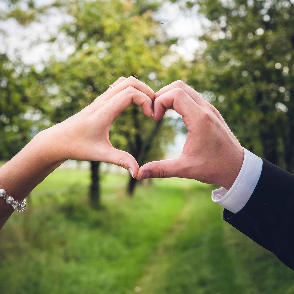 Bride and groom hold up their hands in the shape of a love heart