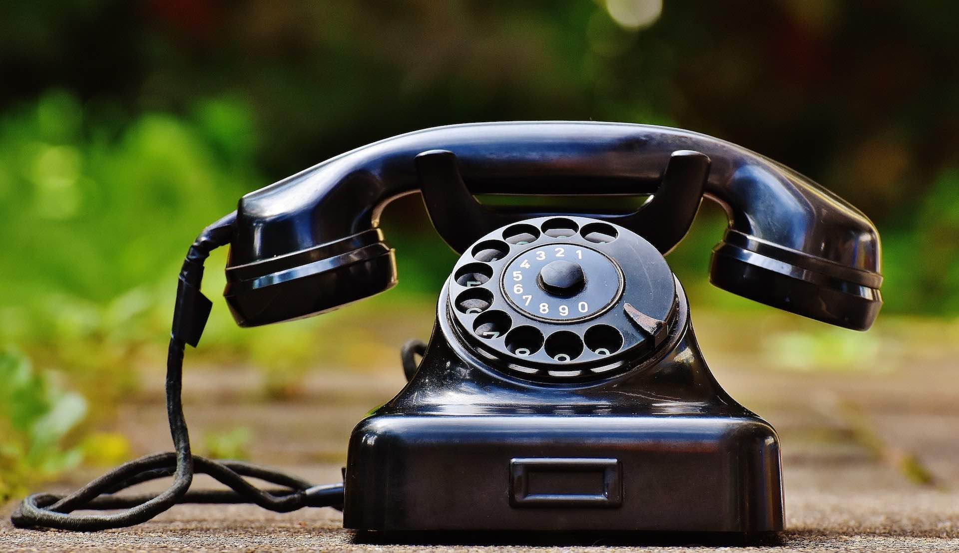 Vintage Black phone handset sitting on the ground outside