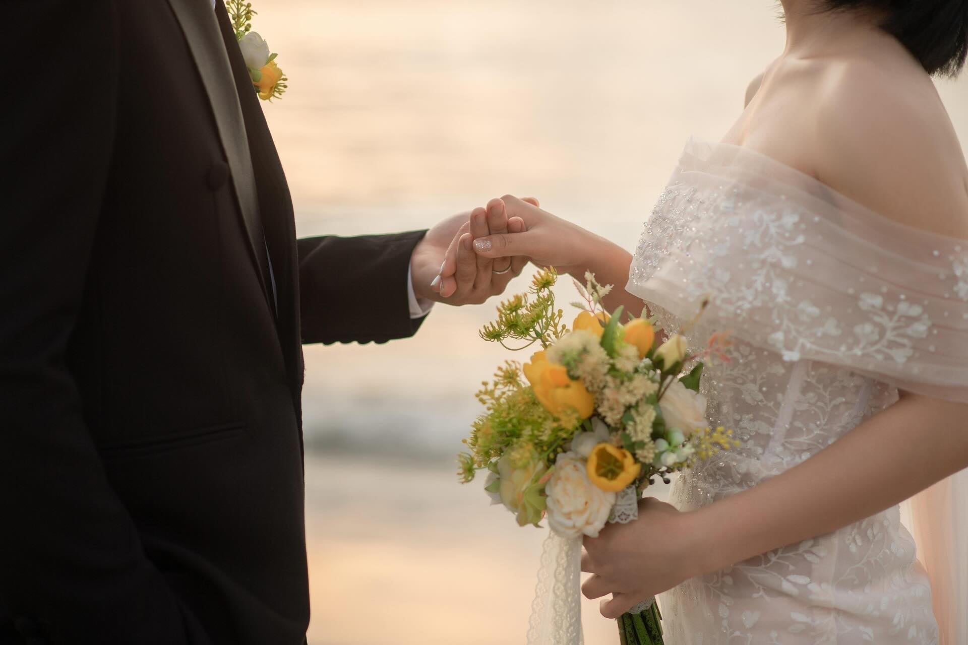Wedding couple holding hands while looking at each other on a beach. 