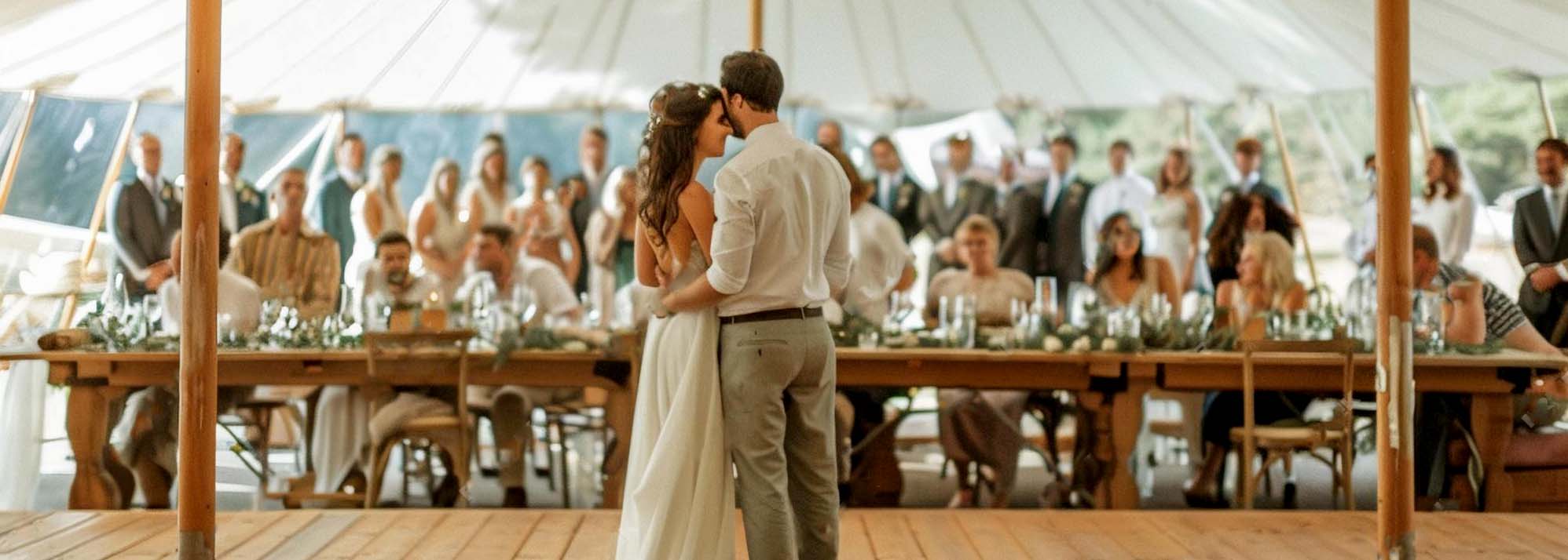 Outdoor wedding tent with couple on dance floor.