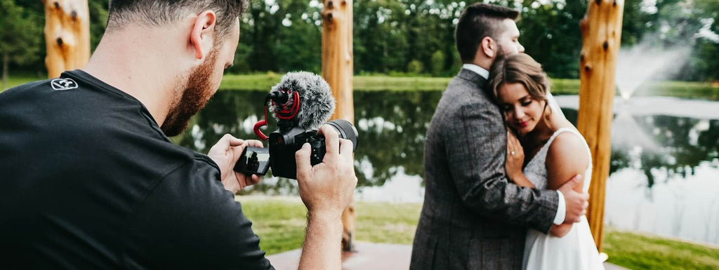 Wedding couple being video recorded by a man holding camera.