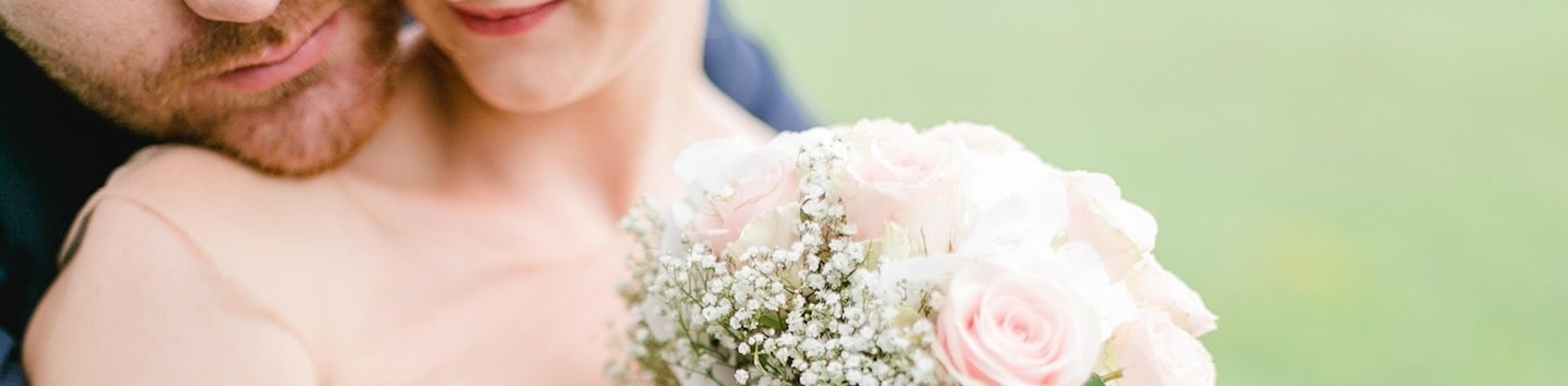 Couple embrace with a floral bouquet being held.