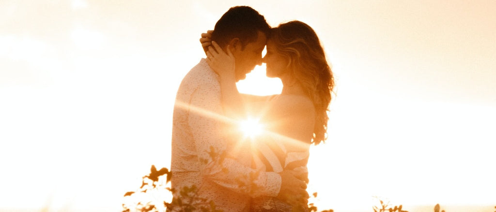 Couple gazing into each others eyes while silhouetted by the sun.