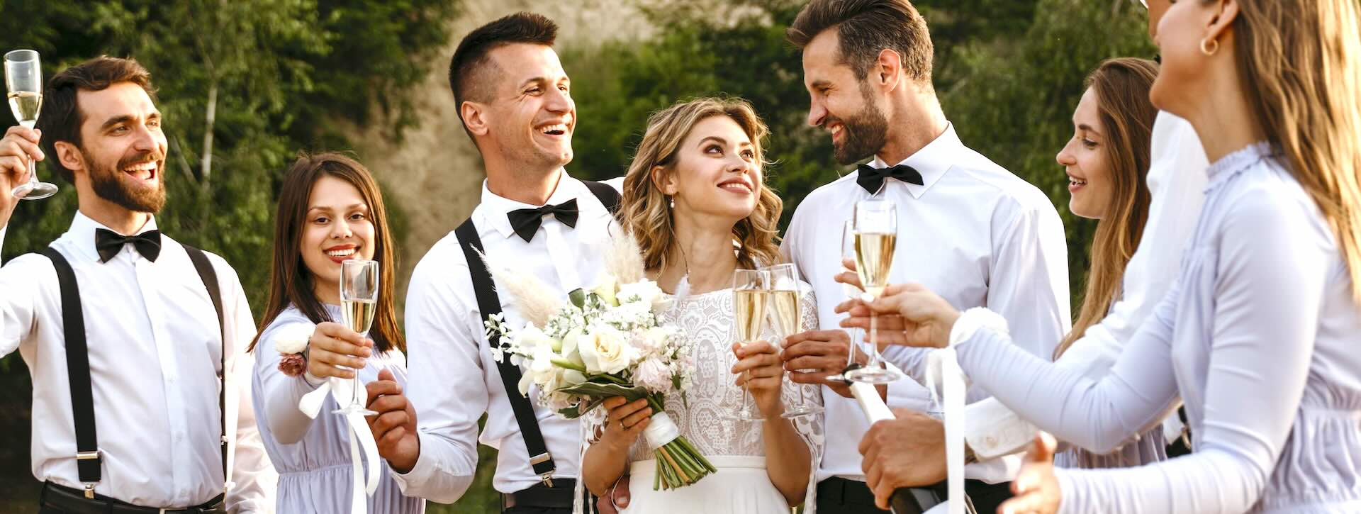 Bride and groom are surrounded by their wedding party making a toast. 