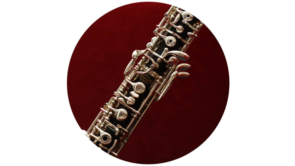 Middle section of oboe with silver plated keys. On a red background
