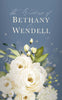 Dusty blue background card with white florals and wedding wording written above. 